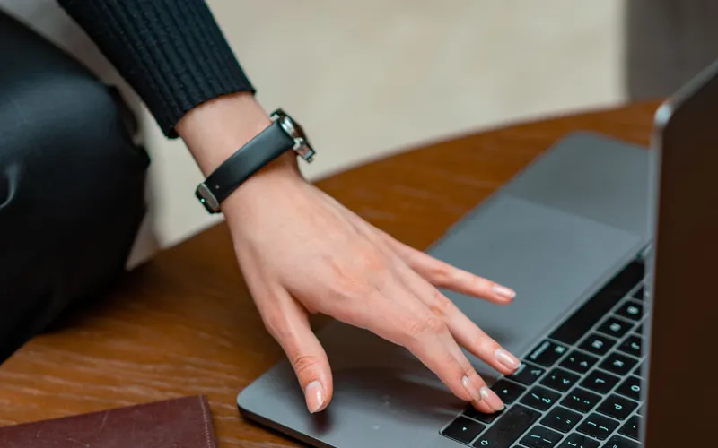 Mano de una mujer sobre una laptop, junto a un pasaporte y unos papeles, representando el papeleo para formalizar un negocio pequeño en Estados Unidos.
